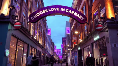 Personas-Con-Máscaras-Faciales-Pasando-Por-Tiendas-Cerradas-Debajo-De-Luces-Navideñas-Con-Temática-De-Pandemia-De-Covid-En-Carnaby-Street-En-El-Extremo-Oeste-De-Londres