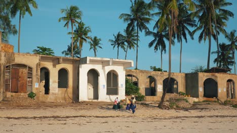 Group-of-children-walking-the-beach-home-from-school-on-late-afternoon,-clear-sunny-day-in-Zanzibar,-Africa