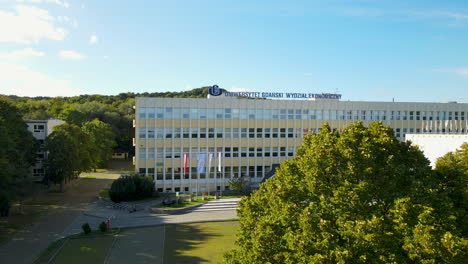 Un-Dron-Aéreo-Revela-Una-Toma-De-La-Fachada-Del-Moderno-Edificio-De-La-Universidad-Polaca-Detrás-De-Un-árbol
