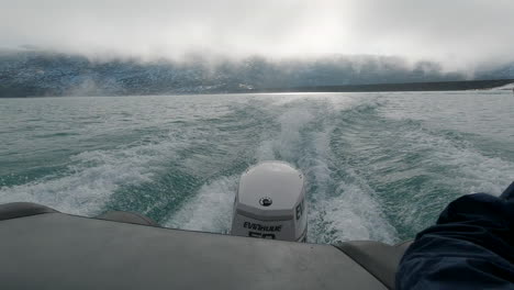 Close-Up-of-the-Motor-of-a-Speedboat-Traveling-Over-a-Bright-Blue-Glacial-Lake-with-a-Snowy-Mountain-Backdrop