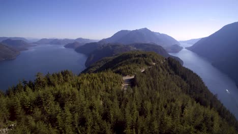 An-wide-aerial-view-of-green-tree-covered-mountains-surrounded-by-lakes