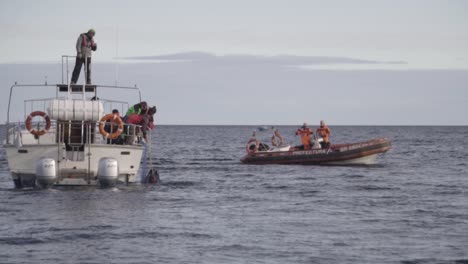 Männer-Auf-Ihren-Booten-Treiben-Mitten-Im-Patagonischen-Meer-Während-Ihres-Nautischen-Trainings-An-Einem-Bewölkten-Tag---Slowmo