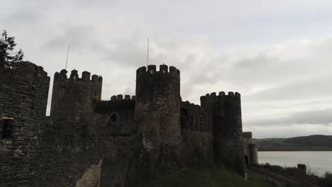 Historical-medieval-Conwy-castle-landmark-aerial-view-pull-back-close-to-walls