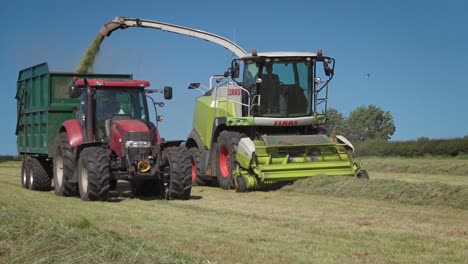 Landwirtschaftliche-Lohnunternehmer-Betreiben-Große-Maschinen,-Um-Reihen-Geschnittenen-Grases-Für-Silage-Winterfutter-Aufzusammeln