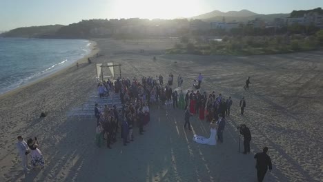 Beautiful-Wedding-with-many-People-on-Beach-During-Sunset,-Aerial-Circling