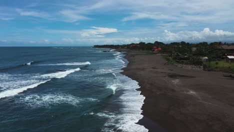 Pererenan-Beach-in-Bali-Indonesia-showing-dark-volcanic-sand,-Aerial-dolly-out-reveal-shot