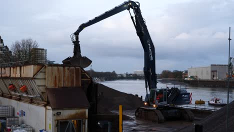 Digger-loading-aggregates-at-a-concrete-plant-on-early-morning-near-Thames-river