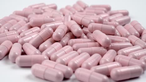 Close-up-of-the-rotation-soft-pink-pills-or-capsules-on-white-background