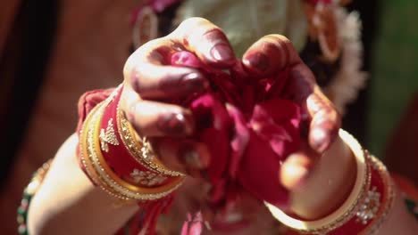 Schöne-Indische-Braut-Trägt-Goldschmuck-Und-Führt-Ein-Hochzeitsritual-Mit-Rosenblütenblättern-Durch