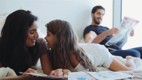 Sweet-Daughter-Kisses-Mother-On-Bed-While-Father-Is-Happily-Watching-Them---full-shot