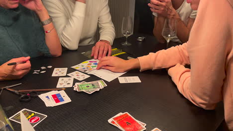 Familie-Spielt-Drinnen-Auf-Einem-Schwarzen-Tisch-Ein-Mystery-Spiel-Namens-„Exit“.