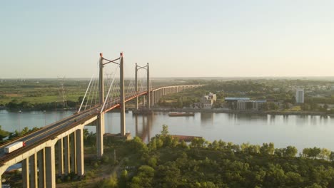 Aerial-shot-flying-alongside-cable-stayed-bridge-crossing-a-big-river-at-golden-hour