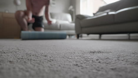 A-man-rolling-out-a-yoga-mat-in-his-living-room-at-home
