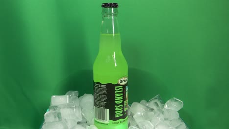 2-3-Botellas-De-Vidrio-De-Bebida-De-Pomelo-Con-Sabor-A-Marca-Grace-Que-Giran-360-Grados-En-Un-Recipiente-Lleno-De-Hielo-Frente-A-Una-Pantalla-Verde