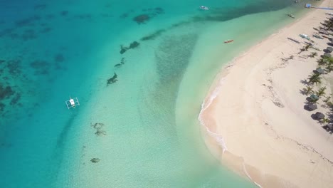 Aerial-tracking-shot-of-blue-green-waters-swashing-up-on-white-sand-beach-in-the-Philippines