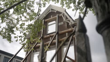 Una-Antigua-Casa-Abandonada-En-Amsterdam,-Con-Ramas-De-árboles-Balanceándose-En-Primer-Plano