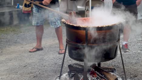 Closeup-of-someone-stirring-steaming-apple-butter-in-a-large-wood-fired-cauldron-outside