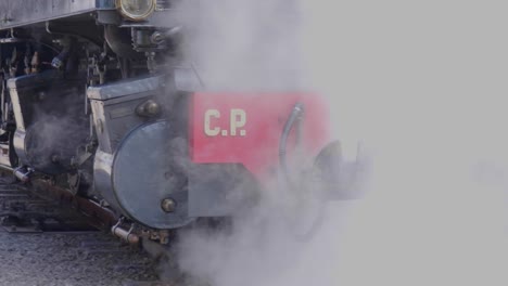 Close-up-shot-of-steam-locomotive-driving-in-reverse-with-lots-of-smoke-and-vapor-Blonay-Chamby-museum-track,-Switzerland