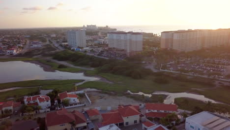 Aerial-sweep-from-hotels-along-the-beach-on-the-Caribbean-sea-during-sunset-to-residential-homes