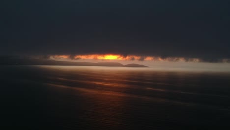 Aerial-Drone-Shot-of-sunset-behind-a-giant-cloud-above-the-ocean