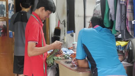 Old-Indonesian-tailor-sewer-sewing---measuring-fabrics-for-colourful-shirt-making-in-local-store