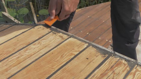 Removing-residual-mastic-from-boat-roof-planking-with-scraper