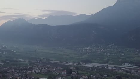 Aerial-panoramic-view-of-Levico-Terme,-Italy,-during-sunrise-with-drone-flying-sideways