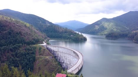 Luftdrohnenaufnahme-Eines-Wunderschönen-Künstlichen-Staudamms-Mit-Den-Wunderschönen-Rumänischen-Bergen-Als-Hintergrund