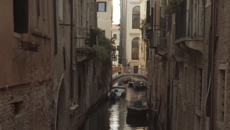 Quiet-narrow-street-where-Old-man-is-walking-on-a-bridge-in-distance,-Venice,-Italy