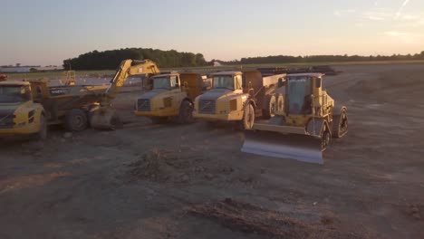 Luftaufnahme-Verschiedener-Schwerer-Volvo--Und-Cat-Maschinen,-Die-Nach-Der-Arbeit-Auf-Einer-Baustelle-Geparkt-Sind