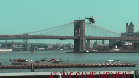 Helicóptero-Despegando-Del-Muelle-6-En-East-River,-Con-El-Puente-De-Brooklyn-Al-Fondo