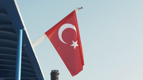 Türkische-Flagge-Am-Heck-Der-Fähre,-Weit-Nach-Unten-Geschossener-Hafen-Von-Mytilini