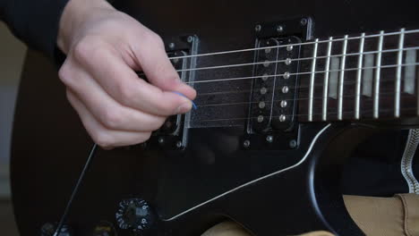 Man-Practising-a-vintage-black-electric-guitar,-rehearsing-chords,-solos-and-octaves-in-a-natural-light-environment.