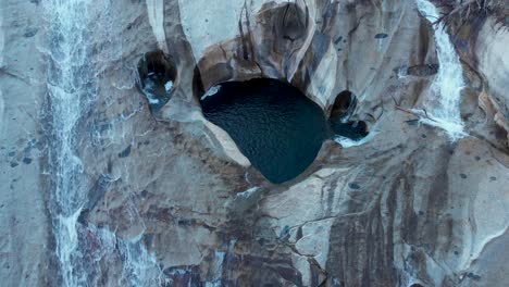 Aerial-top-view-shot-descending-on-cascading-waterfalls-and-deep-pools-of-water-in-granite-rock