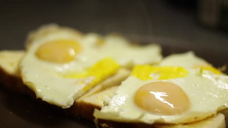 Tilt-down-close-up-shot-of-fried-eggs,-still-steaming-on-two-slices-of-white-bread