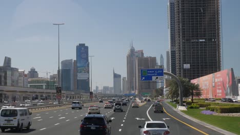 Coches-Circulando-Por-Una-Enorme-Autopista-A-Través-Del-Puerto-Deportivo-De-Dubai-Alrededor-De-Enormes-Rascacielos