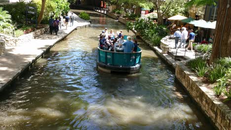 Electric-boat-with-tourists-flows-down-old-canal-in-San-Antonio-Riverwalk