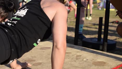 Athletic-caucasian-women-doing-press-ups,-push-ups-at-a-cross-fit-competition,-a-popular-military-exercise-great-for-developing-the-pectoral,-bicep-and-tricep-muscles