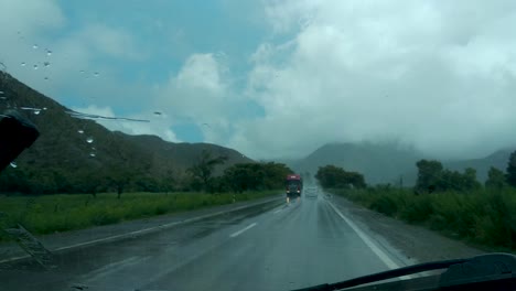 Driving-through-a-rainstorm-on-a-2-lane-road,-seen-from-the-front-seat-of-the-vehicle