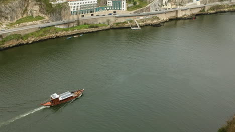 Aerial-dolly-shot-of-a-boat-cruising-on-the-Duoro,-Porto,-Portugal