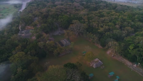 AERIAL:-Aerial-shot-of-Mayan-archaeological-site-amid-deep-green-forest-in-Copan,-Honduras