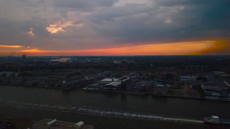 Fliegen-über-Die-Skyline-Von-Amsterdam-Bei-Sonnenuntergang-Per-Drohne-über-Den-Ij-Fluss-In-Der-Nähe-Des-Hauptbahnhofs-Mit-Wunderschönem-Roten-Himmel-Und-Weißem-Zug-In-Richtung-Zum-Bahnhof