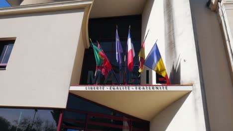 Zeitlupenaufnahme-Von-Nationalflaggen,-Die-Auf-Dem-Eingangsdach-Eines-Gebäudes-Hängen