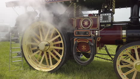 Steam-pouring-out-from-a-red-vintage-traction-engine-while-mechanics-work-on-it