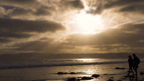 Pareja-Camina-En-El-Surf-En-Silueta-En-Coronado,-California,-Playa-Al-Atardecer