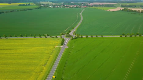 Aerial-view-of-crop-fields-with-road-and-rotary-traffic-winding-through-it