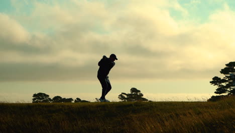 Silueta-De-Golfista-Haciendo-Un-Swing-Y-Un-Segundo-Jugador-Se-Acerca,-Hermosas-Nubes-Y-Cielo,-Bandon-Dunes-Golf-Resort