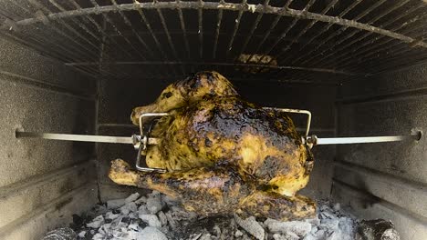Rotisserie-Chicken-rotating-in-a-wood-and-charcoal-fire-brick-bbq-grilling-in-slow-motion