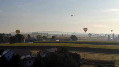 Vista-Aérea-Por-Drones-De-Globos-Aerostáticos-En-El-País-Amish,-Pensilvania-Con-Parapente-Motorizado-Volando