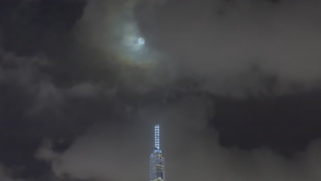 Night-time-lapse-of-Landmark-building-with-full-moon-and-dramatic-sky-in-Ho-Chi-Minh-City,-Vietnam